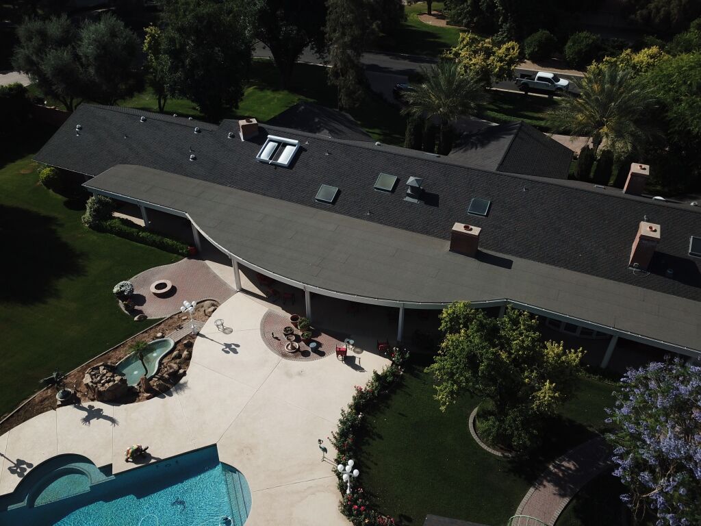 Aerial view of luxury home with curved roofline, swimming pool and landscaped yard