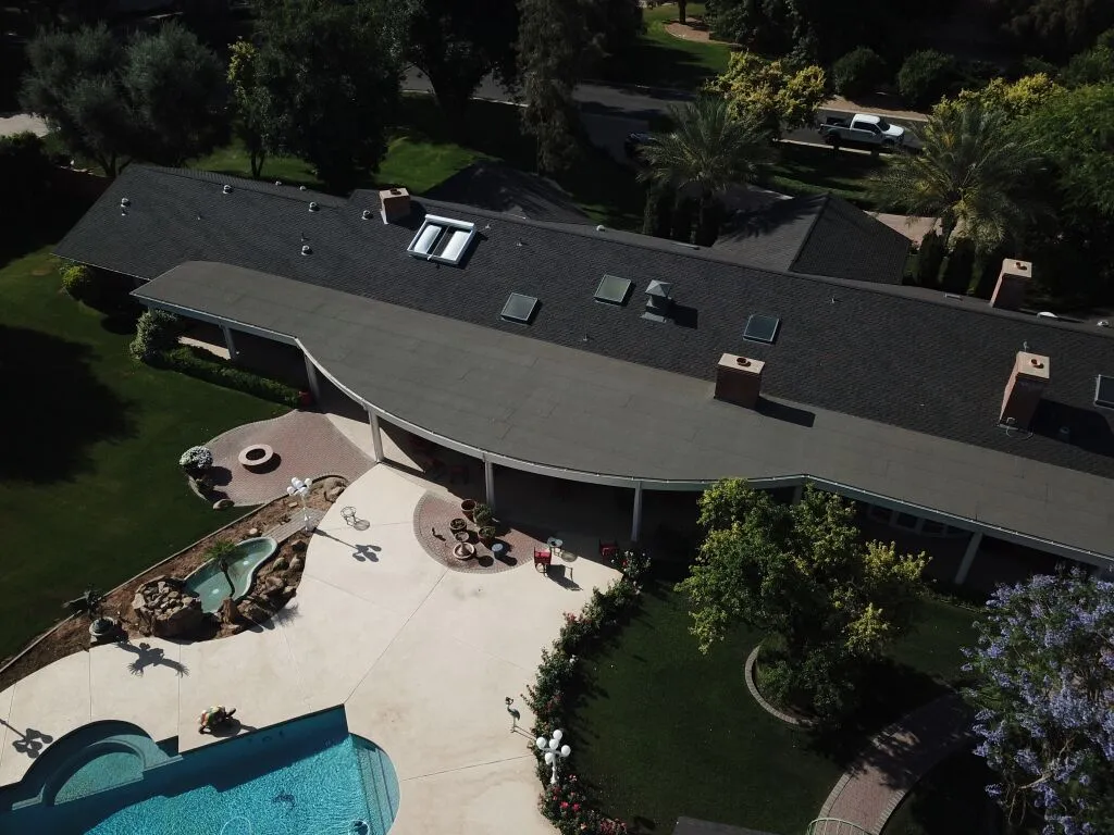 Aerial view of luxury home with curved roofline, swimming pool and landscaped yard