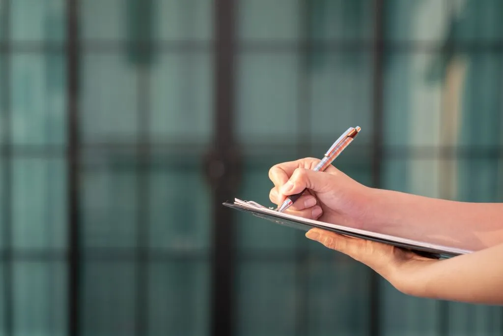 a hand holding a pen and notebook