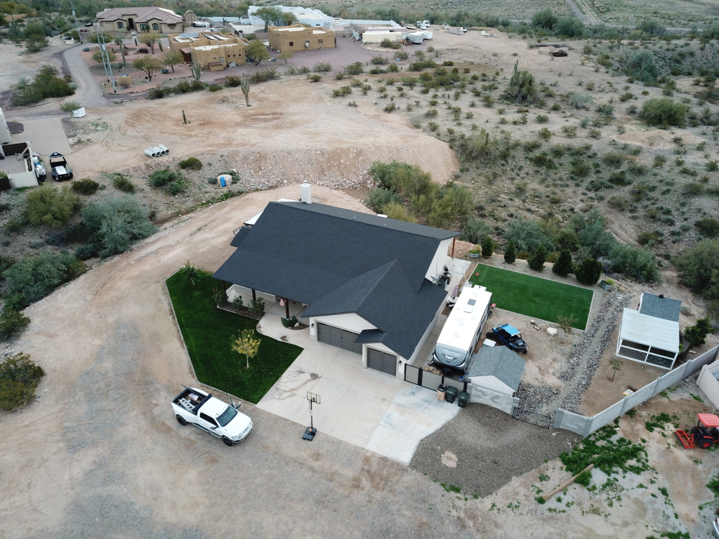 a house with a driveway and cars in the middle of a desert