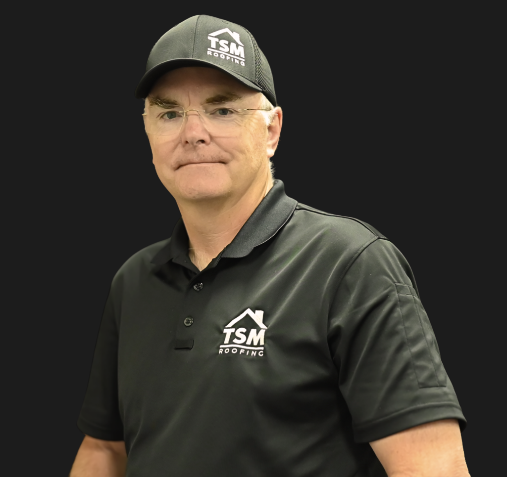 Professional man in TSM Roofing branded polo shirt and cap wearing glasses