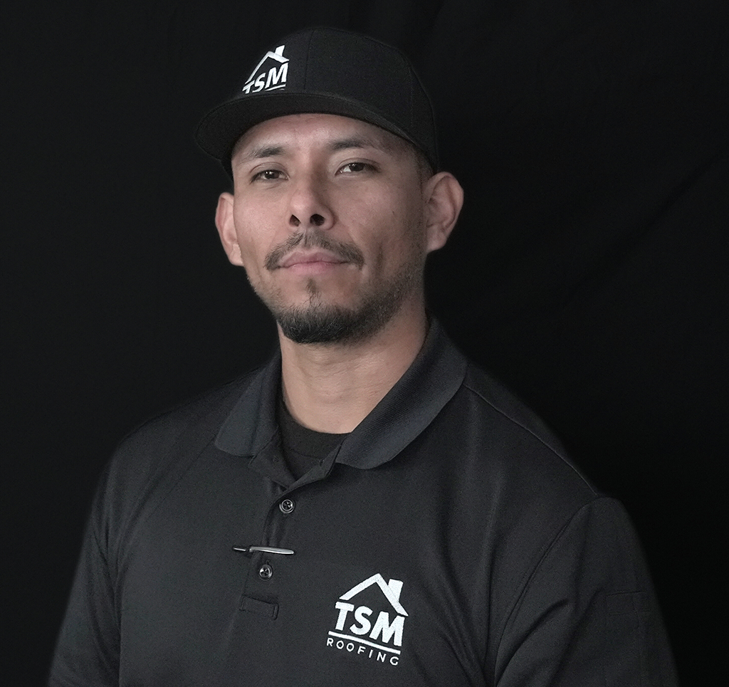 Man in TSM Roofing uniform posing professionally against a dark background.