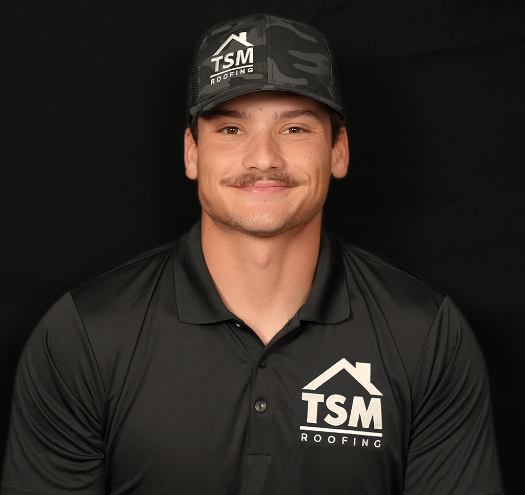 Man in black TSM Roofing attire smiling at the camera