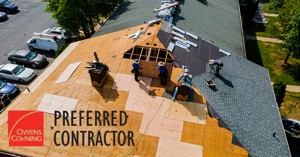 Roofers work on large residential roof under construction
