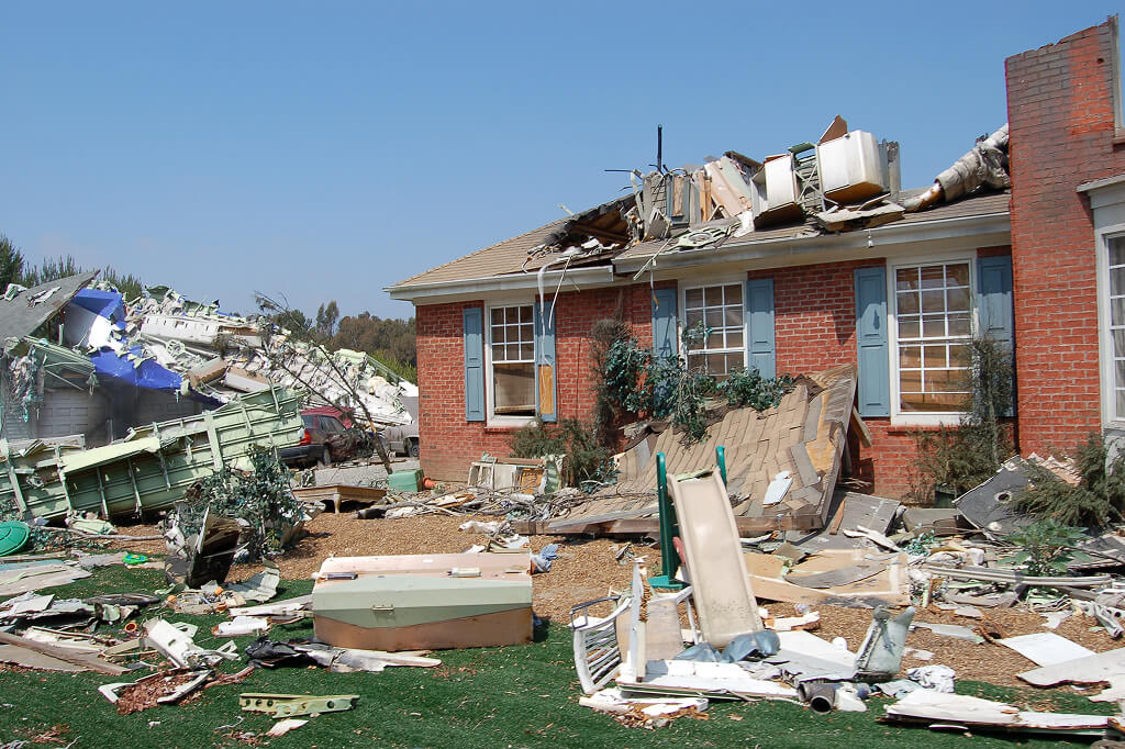 Tornado damage with debris scattered around a partly destroyed brick house.