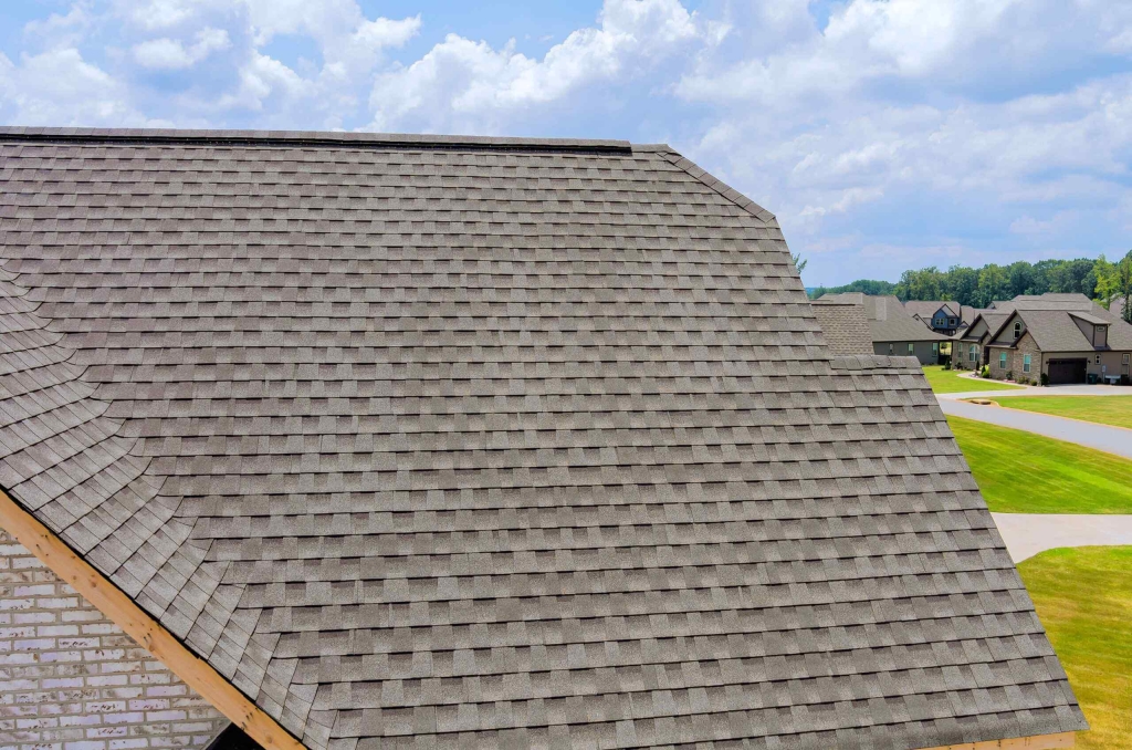Close-up of modern asphalt shingle roof against cloudy sky background