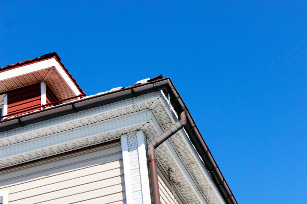 Close-up of a house roof with gutters under a clear blue sky