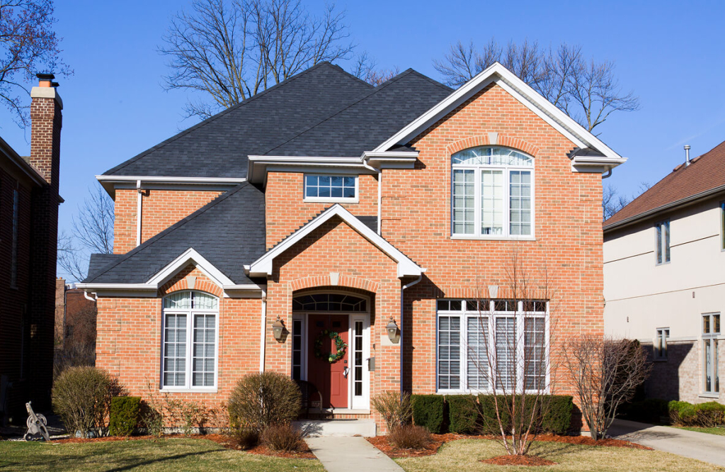 Charming brick suburban house with a gabled roof and manicured lawn