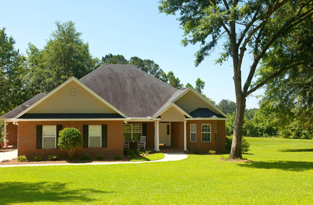 Charming brick house with manicured lawn, surrounded by trees.