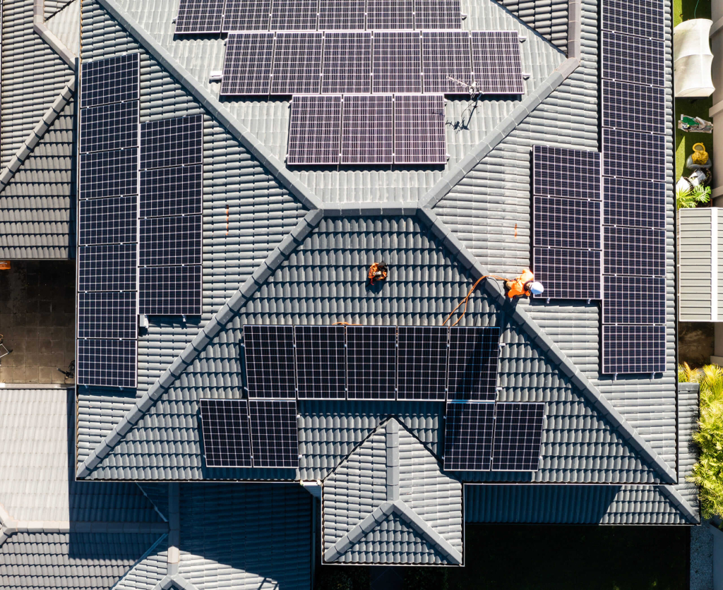 Top view of solar panels installed on a residential rooftop with workers.